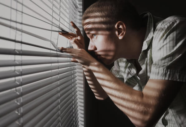 мужчина смотрит через жалюзи